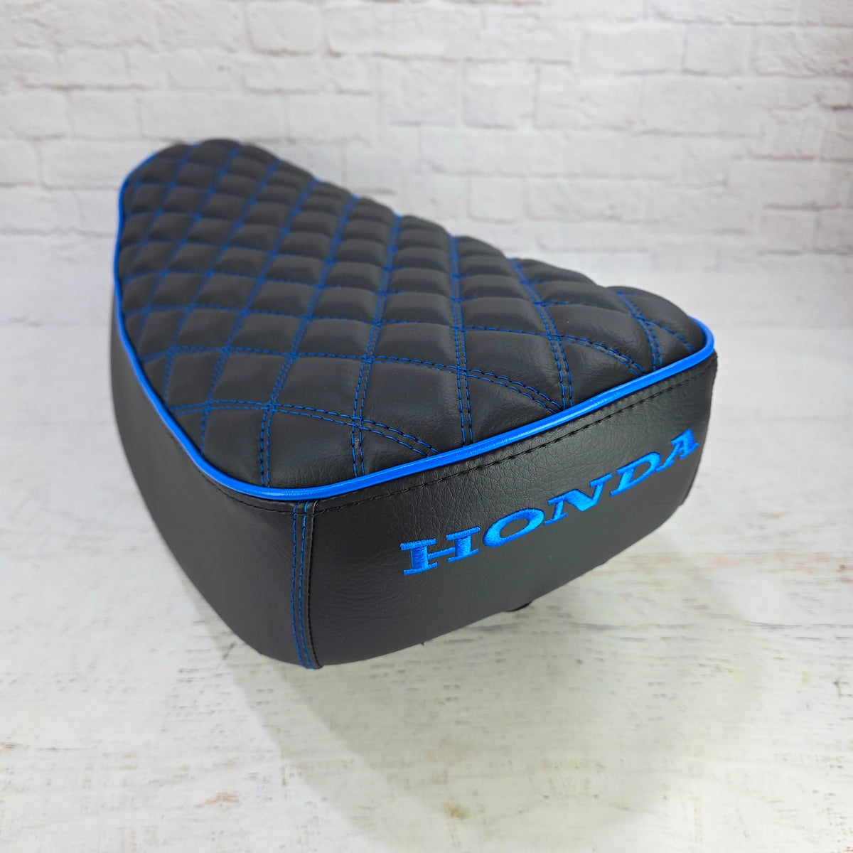 Rear angled view of a black double-diamond Honda DAX 125 cover with vivid blue piping and blue Honda embroidery, handmade by Cheeky Seats