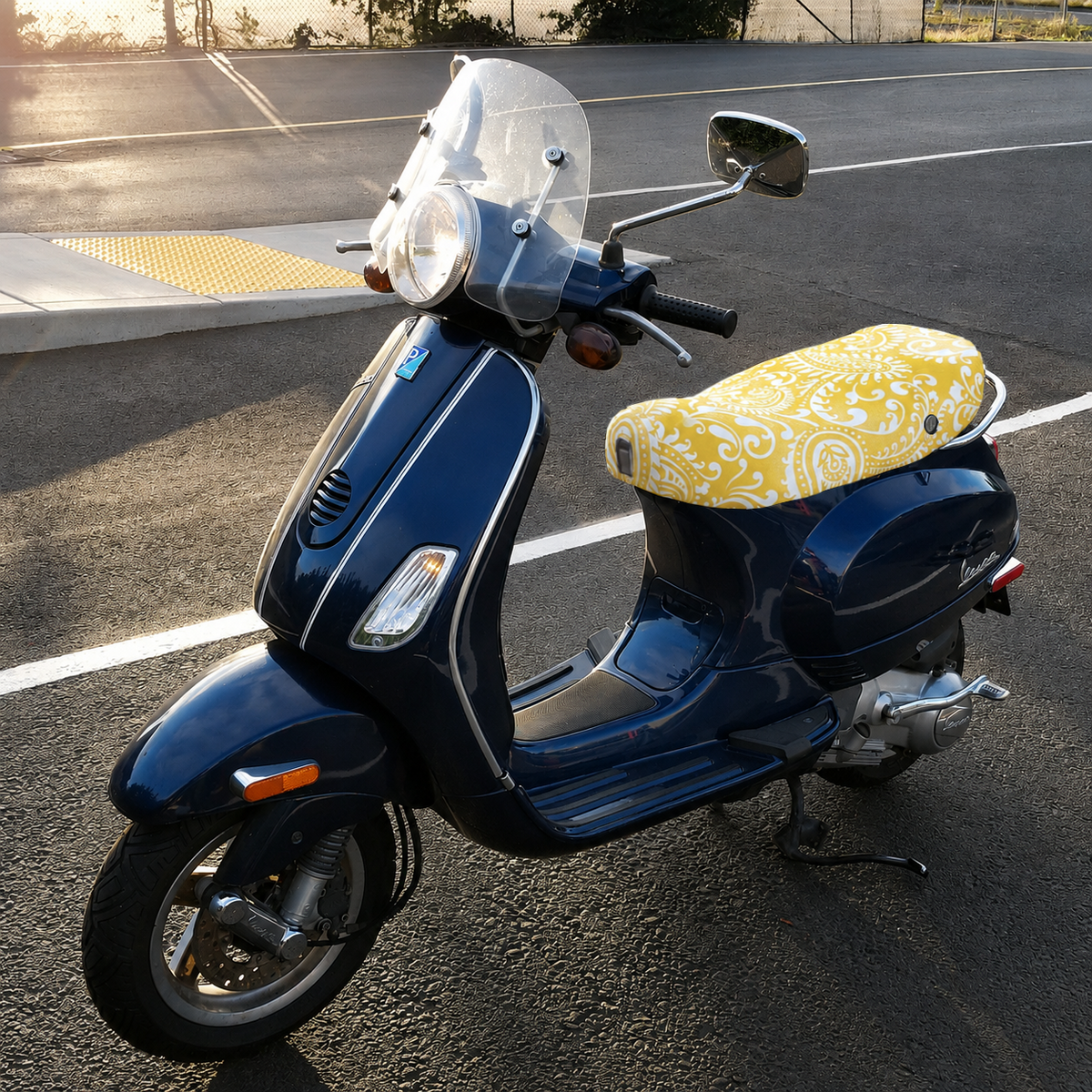 Yellow Paisley breathable seat cover fitted to a dark blue Vespa LX, showing the bright custom fit, handmade by Cheeky Seats.