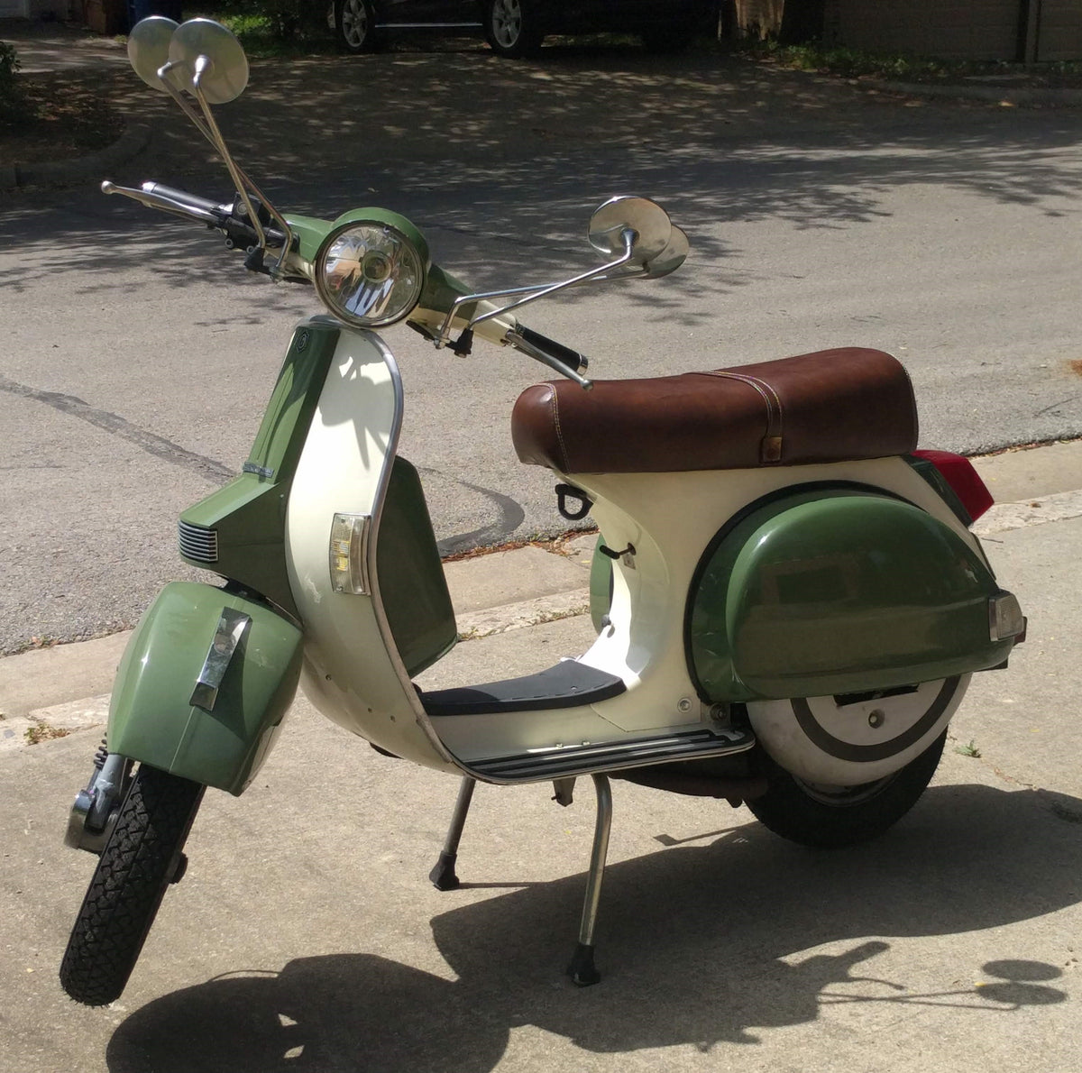 Front three-quarter view of a green and cream Genuine Stella with a handmade Cheeky Seats whiskey-brown seat cover