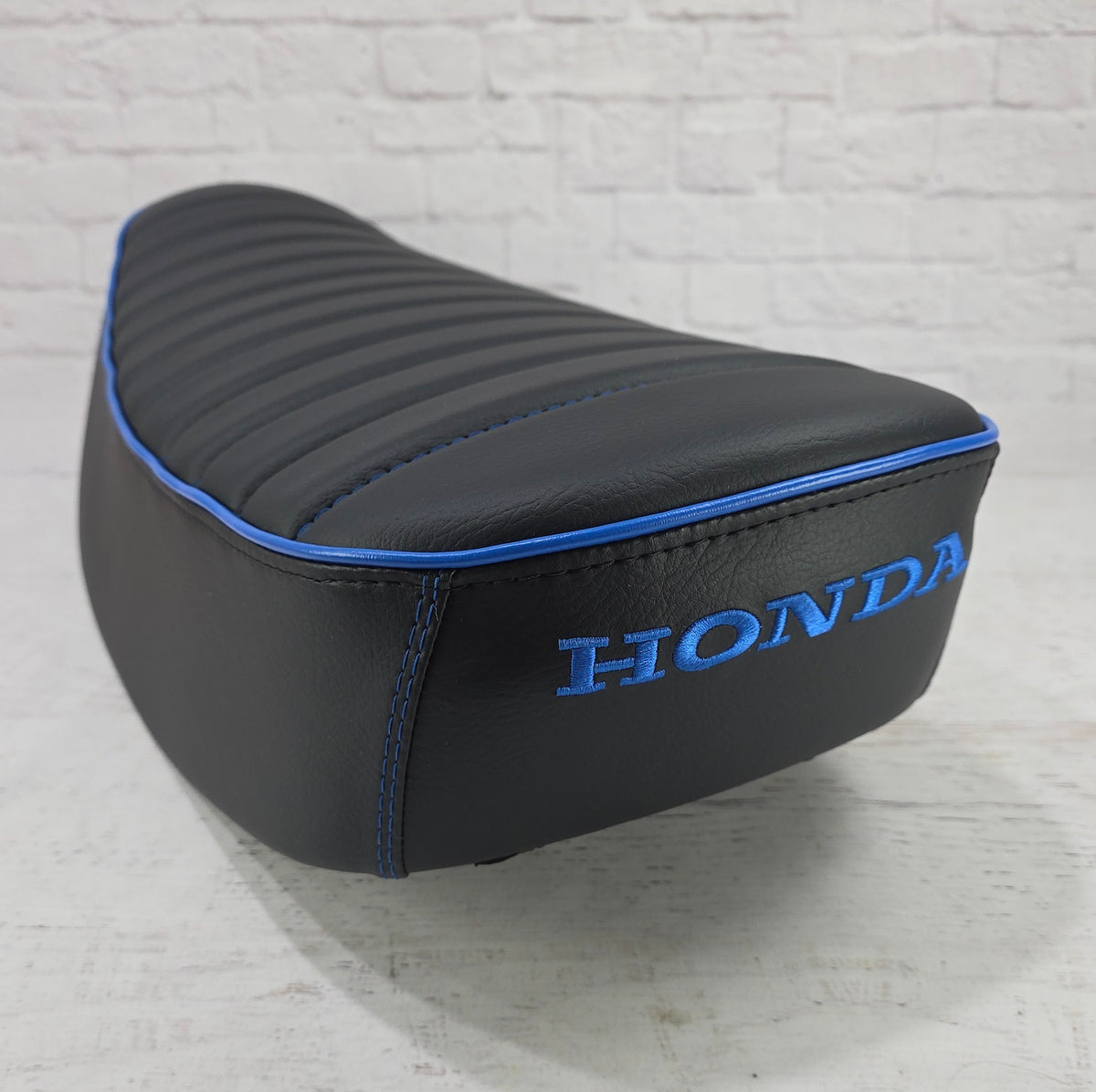 Rear angled view of a black Honda DAX 125 cover with vivid blue stitching, piping and Honda embroidery, handmade by Cheeky Seats