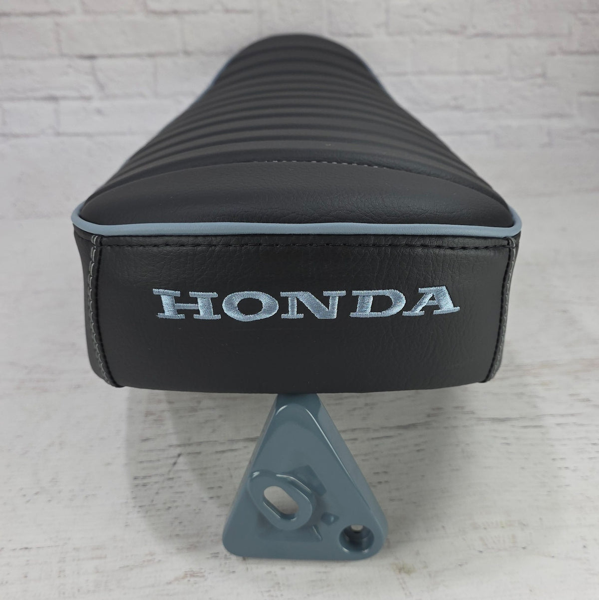 Rear view of a black Honda DAX 125 tuck-and-roll cover with Pearl Gray piping, Honda embroidery and headlight bracket used as a color swatch, handmade by Cheeky Seats
